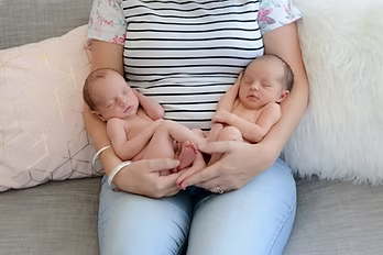 A parent cradling newborn twins